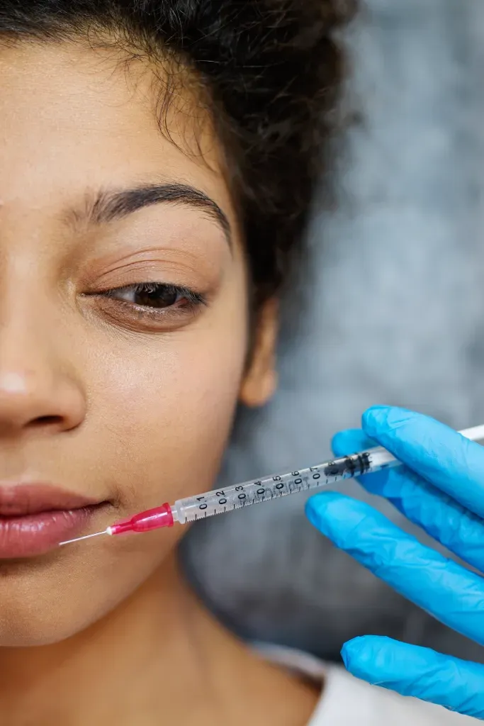 Dentiste administrant une injection de Botox thérapeutique sur une patiente, au niveau de la mâchoire.